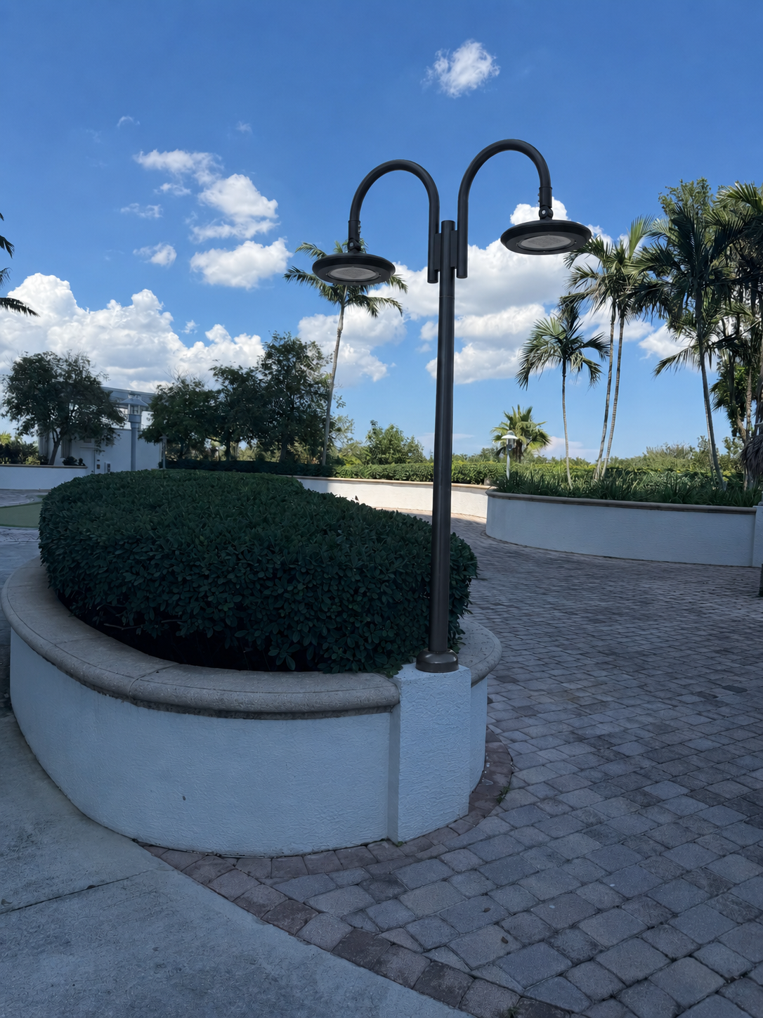 Concept rendering of the new twin-head goose-neck LED garden lamp installed on the same planter pedestal, anthracite finish, two flat disc-style luminaires throwing light in both directions.